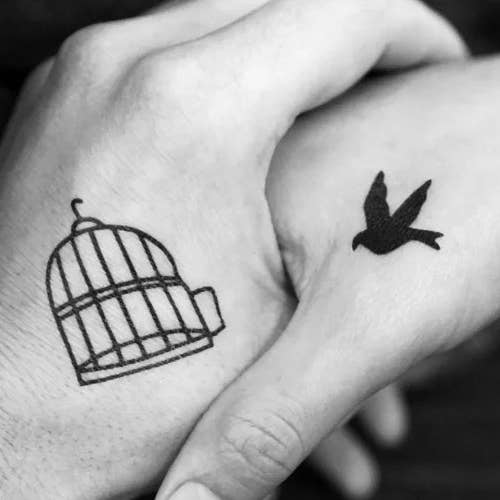 small hand tattoo of a bird and a cage